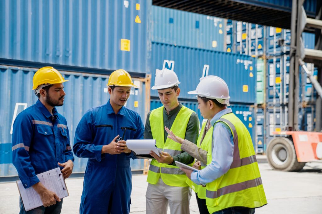 Foremans are discussing for stack container at cargo site logistics service transportation.